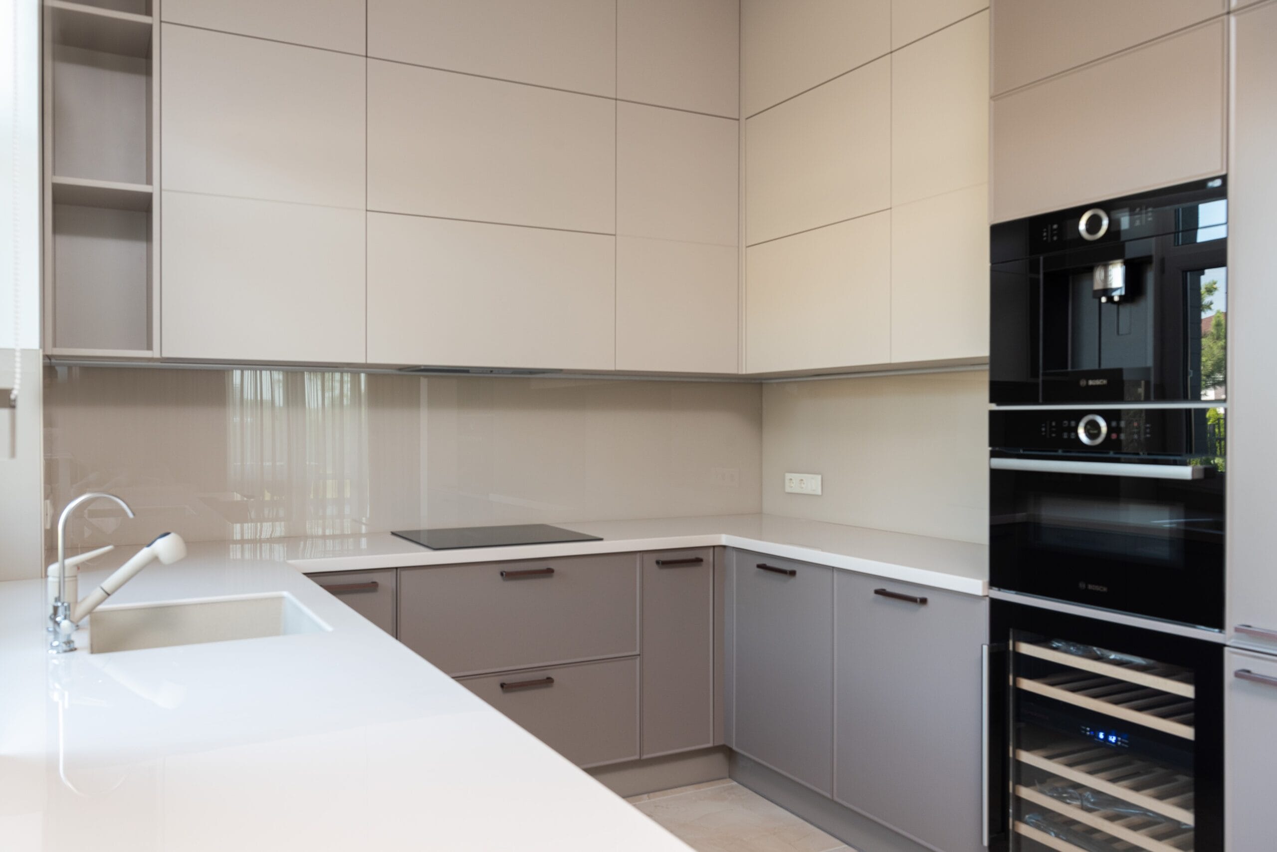 a kitchen with grey cabinets and a wine refrigerator, in the style of light black and light beige