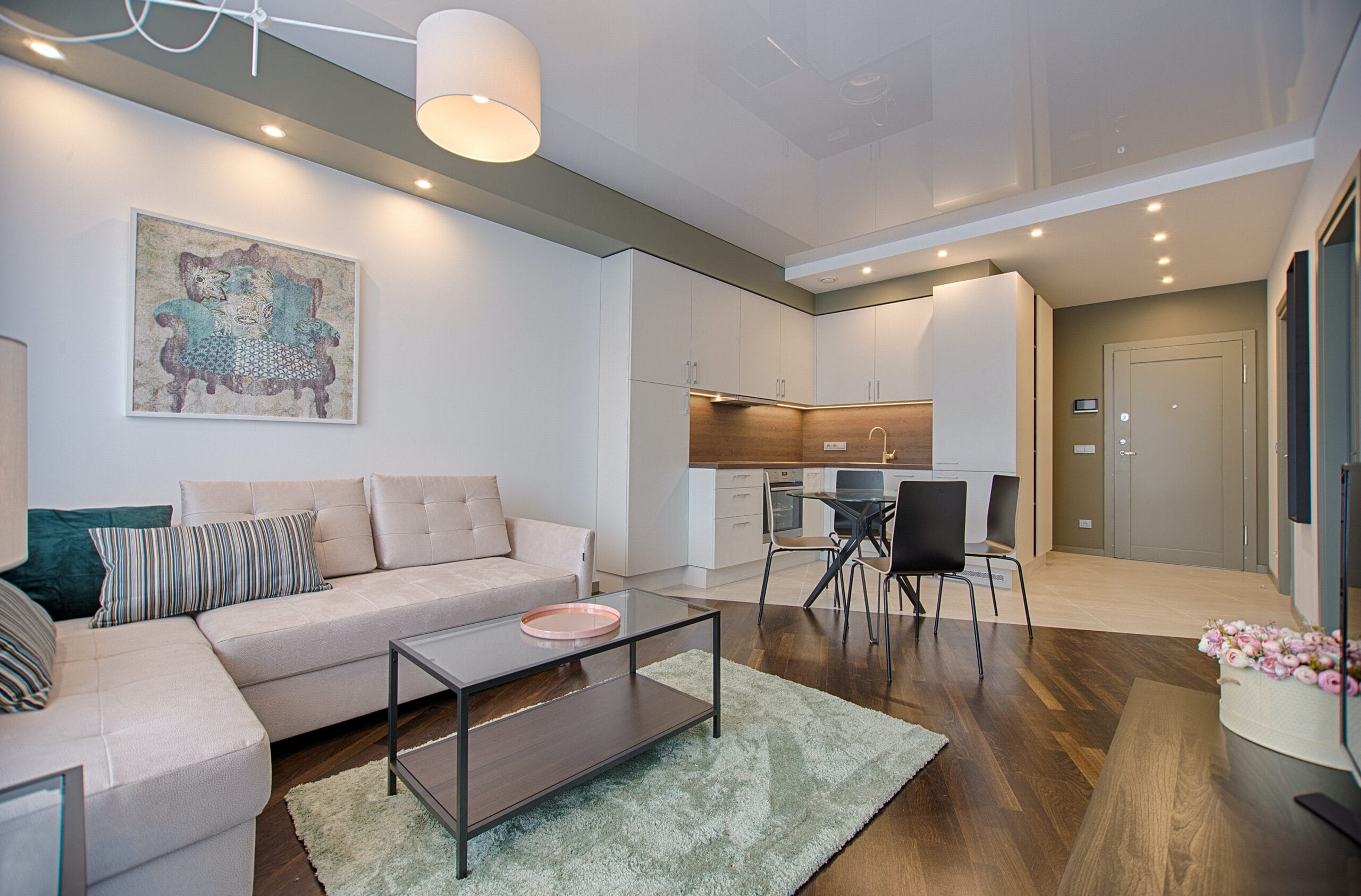 a living room with hardwood floors, kitchen dining area white leather furniture