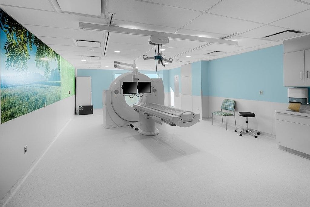 Salle de scanner avec décor mural apaisant et équipement médical moderne, rénovée par MARORENO